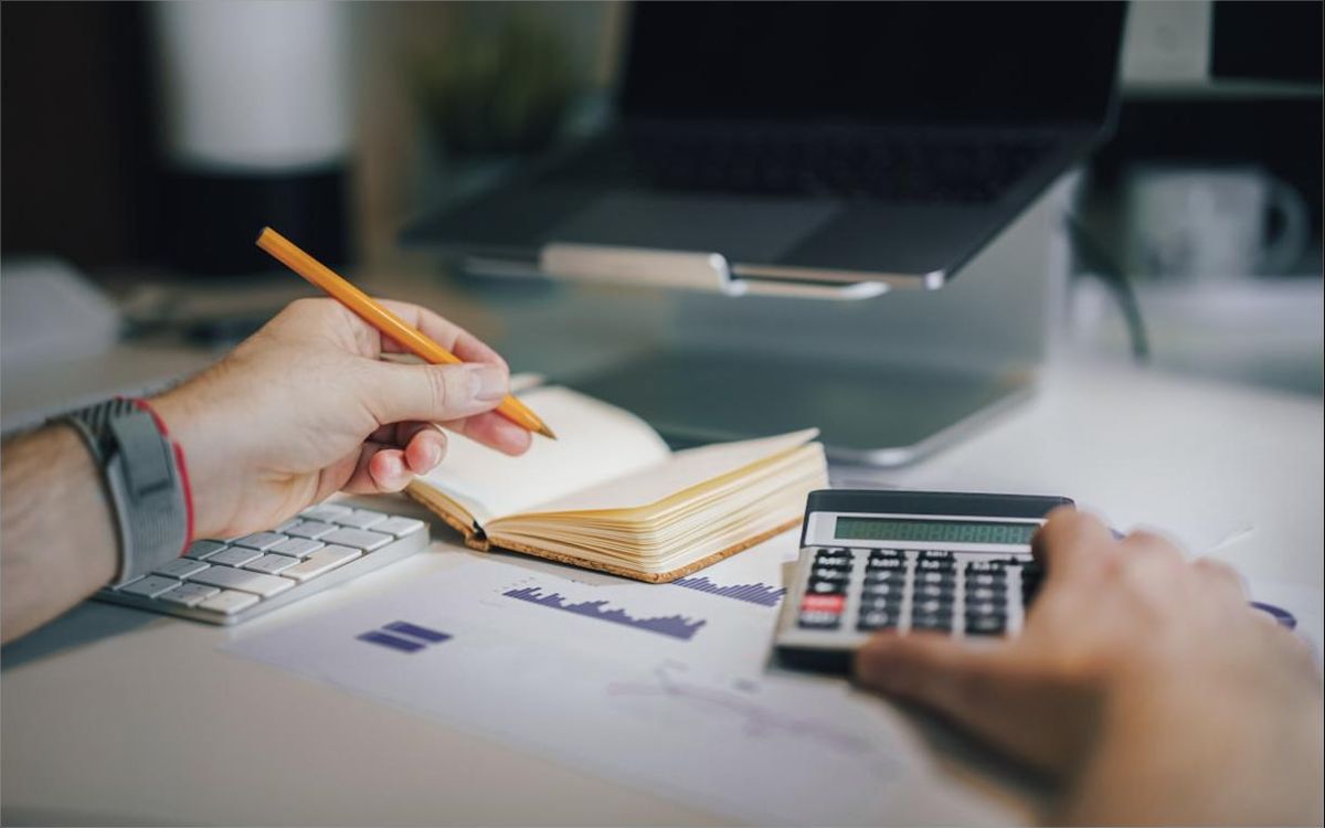 Accountant working through ledgers with a calculator at month-end